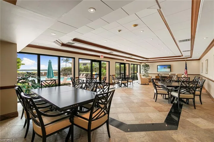 Dining area with ornamental molding, a tray ceiling, recessed lighting, and stone tile flooring