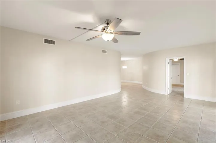 Empty room with ceiling fan and light tile patterned floors