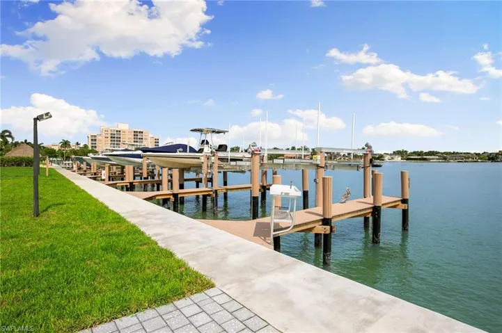 Dock area with boat lift, a water view, and a lawn