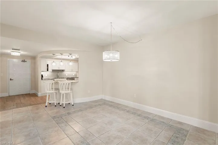 Unfurnished living room with light tile patterned flooring and baseboards