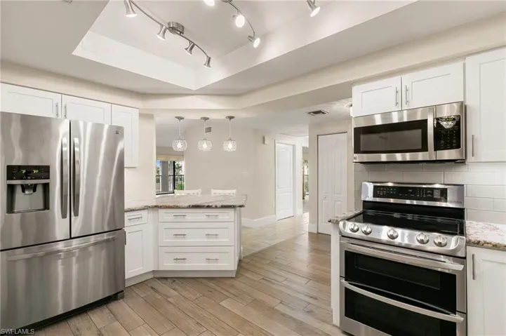 Kitchen with appliances with stainless steel finishes, a peninsula, and white cabinets