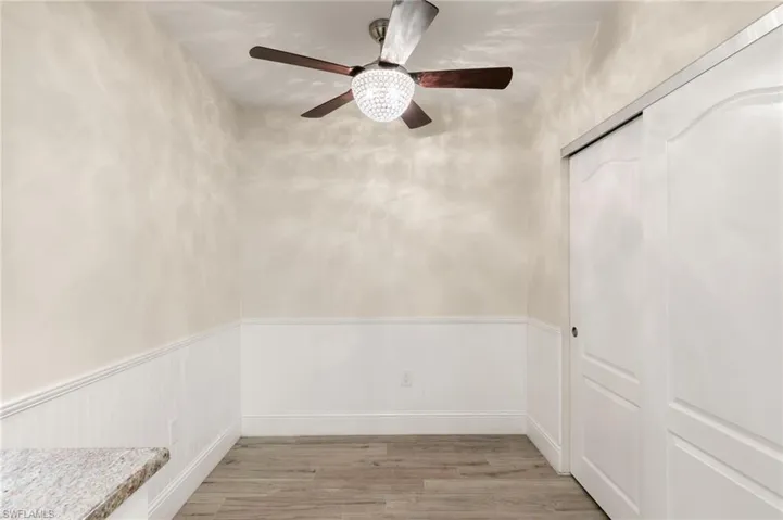 Unfurnished room with a wainscoted wall, light wood-type flooring, and a ceiling fan
