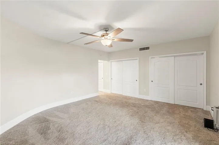 Unfurnished bedroom with two closets, carpet flooring, and ceiling fan