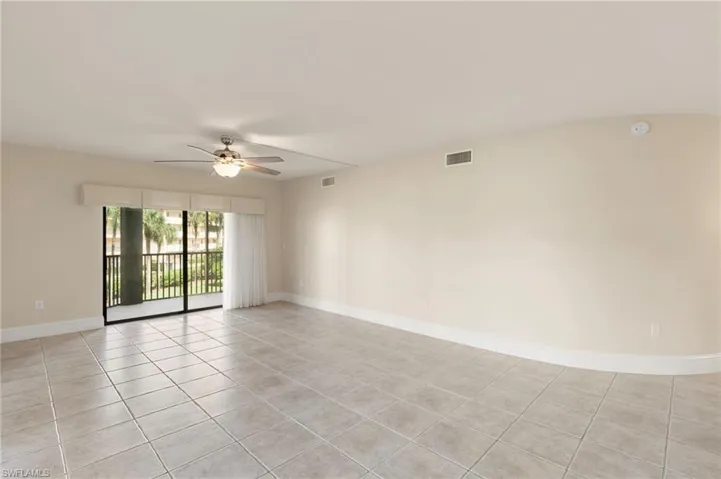 Empty room featuring light tile patterned flooring and ceiling fan