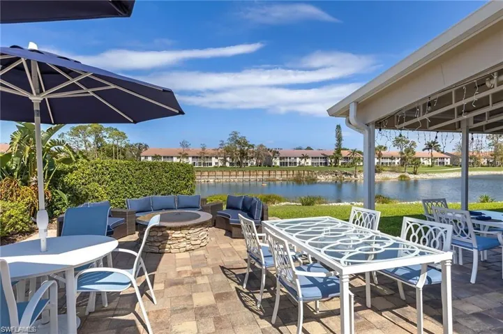 View of patio with outdoor dining space, a water view, an outdoor living space with a fire pit, and a residential view