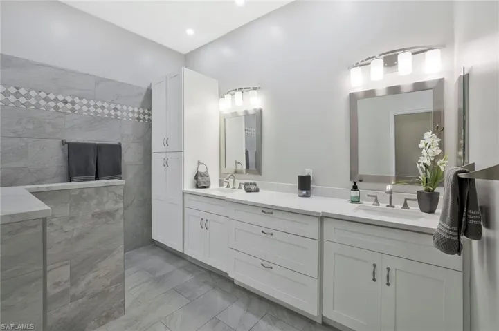 Bathroom featuring quartz counters, double vanity, drawers and lots of cabinets