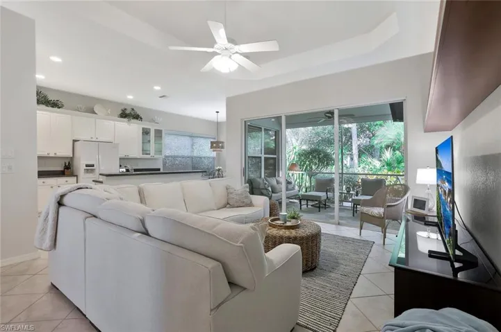Living room with Tray Ceiling and a wealth of natural light, and light tile floor