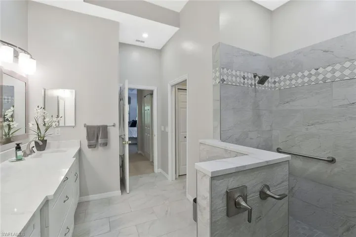 large walk in shower with wall to ceiling tile, private commode room