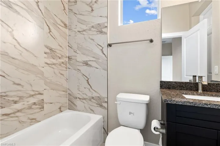 Third Bathroom with vanity, shower / bathtub combination, and a textured wall
