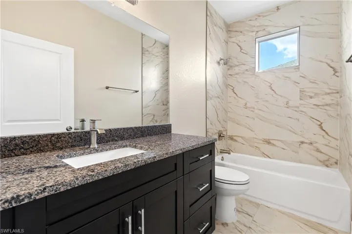 Second bathroom featuring bathtub / shower combination, vanity, and light marble finish flooring