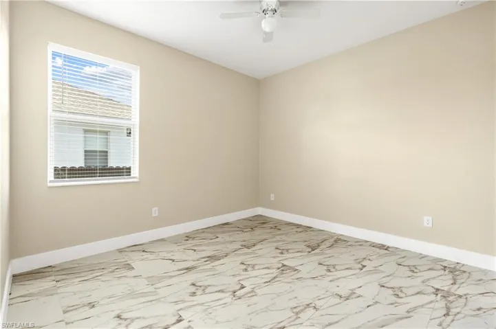 Fourth bedroom featuring light marble finish floors and a ceiling fan