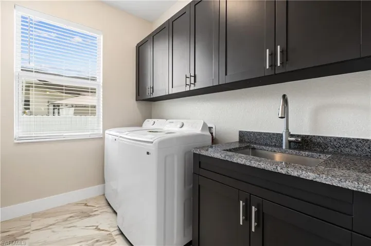 Laundry area with cabinet space, light marble finish flooring, and washing machine and clothes dryer