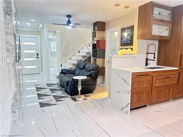Living room featuring a ceiling fan, stairs, and light marble finish floors