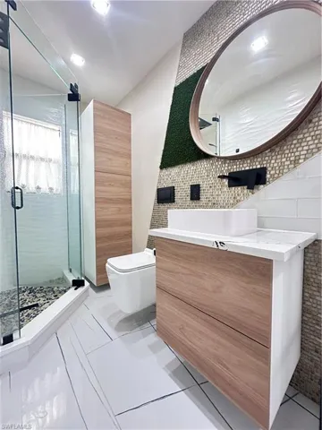 Full bath featuring tile walls, vanity, a shower stall, and tile patterned floors