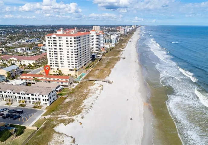 Aerial view of apartment complex and waterfront with a beach