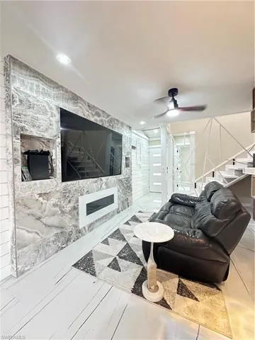 Living area featuring ceiling fan and stairs