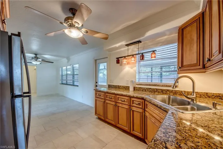 Kitchen featuring freestanding refrigerator, a sink, brown cabinetry, and ornamental molding