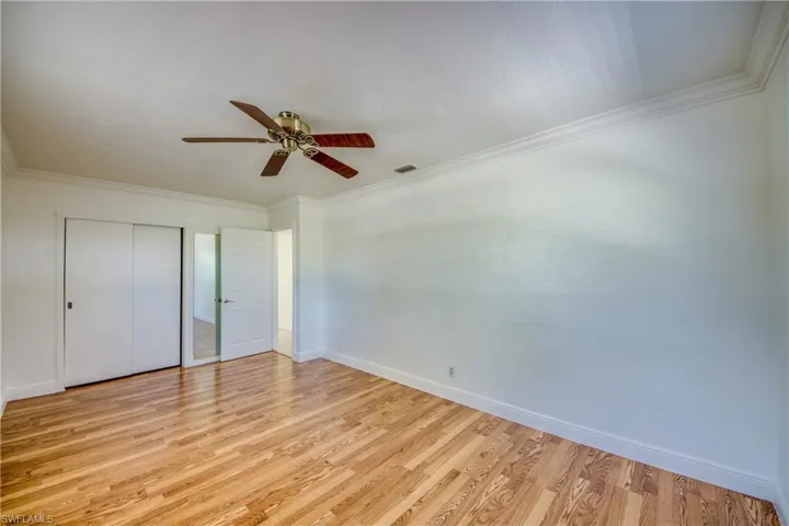 Unfurnished bedroom featuring light wood-style floors, ornamental molding, baseboards, a closet, and a ceiling fan