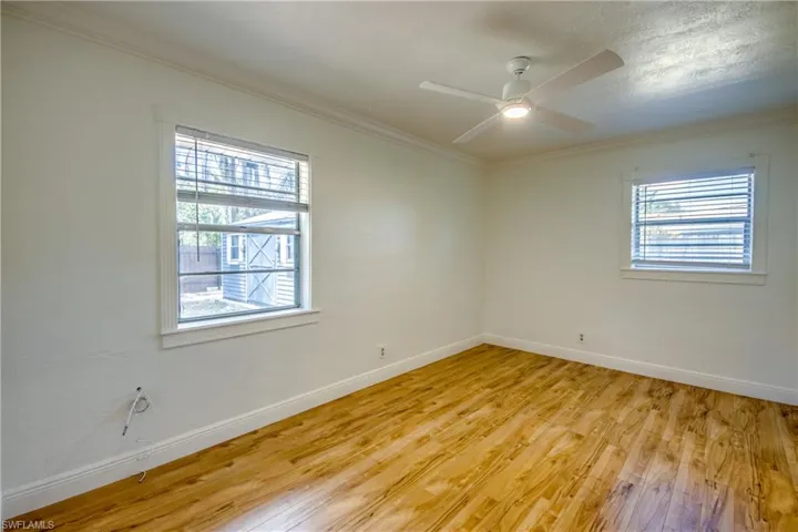 Unfurnished room with light wood-type flooring, baseboards, crown molding, and a ceiling fan