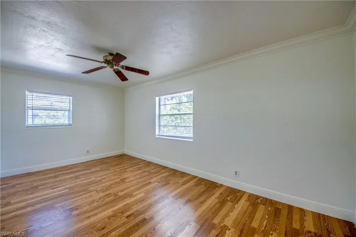 Unfurnished room featuring light wood-style floors, baseboards, ceiling fan, and ornamental molding