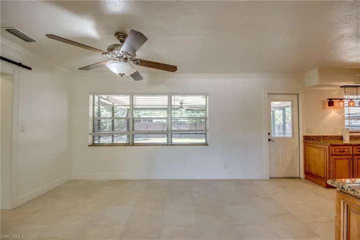 Spare room with crown molding, a barn door, a ceiling fan, baseboards, and a textured ceiling