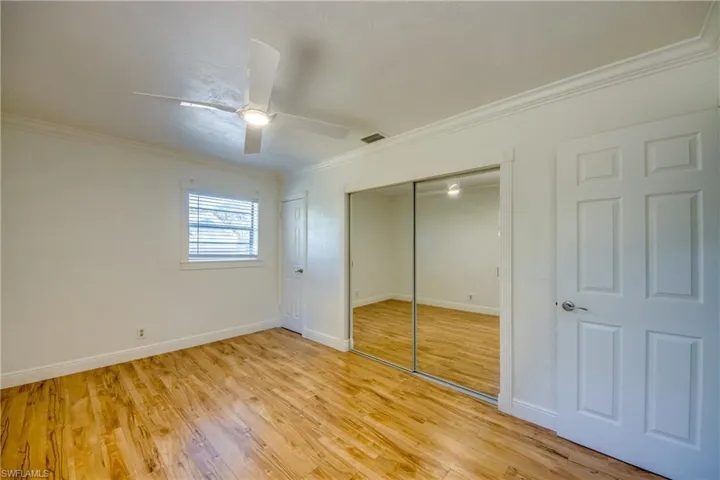 Unfurnished bedroom featuring crown molding, light wood-style flooring, baseboards, a closet, and a ceiling fan