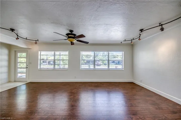 Empty room with track lighting, hardwood / wood-style floors, a ceiling fan, a textured ceiling, and ornamental molding