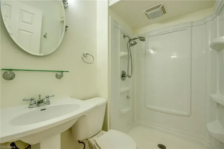 Bathroom with a shower stall, toilet, and a sink