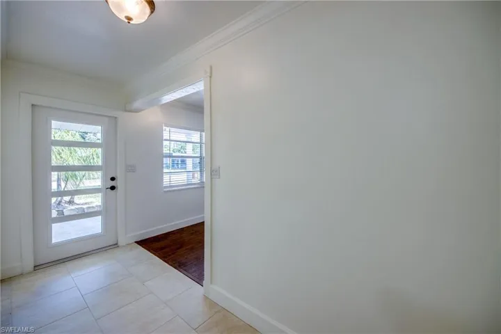 Entryway featuring crown molding, baseboards, and light tile patterned floors