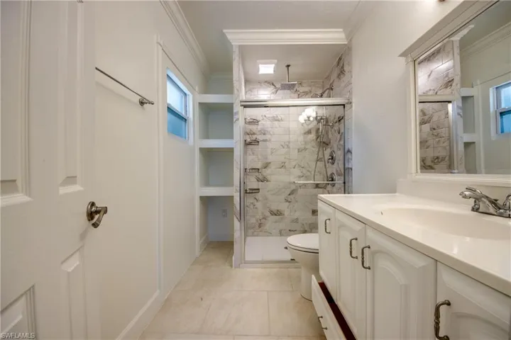 Full bath with a shower stall, crown molding, toilet, vanity, and tile patterned flooring