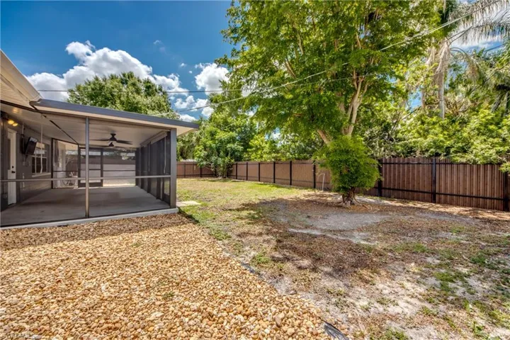 Fenced backyard with a sunroom, a ceiling fan, and a patio