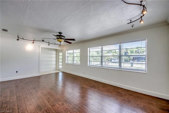 Unfurnished room featuring a textured ceiling, track lighting, ceiling fan, ornamental molding, and baseboards
