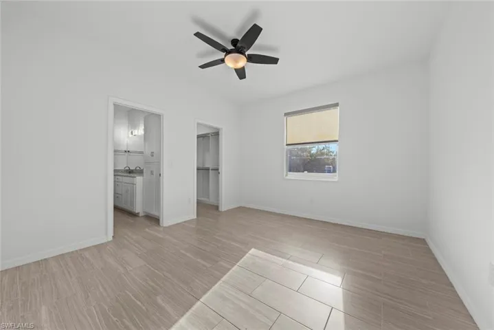 Unfurnished bedroom with ceiling fan, a walk in closet, light hardwood / wood-style floors, and a closet