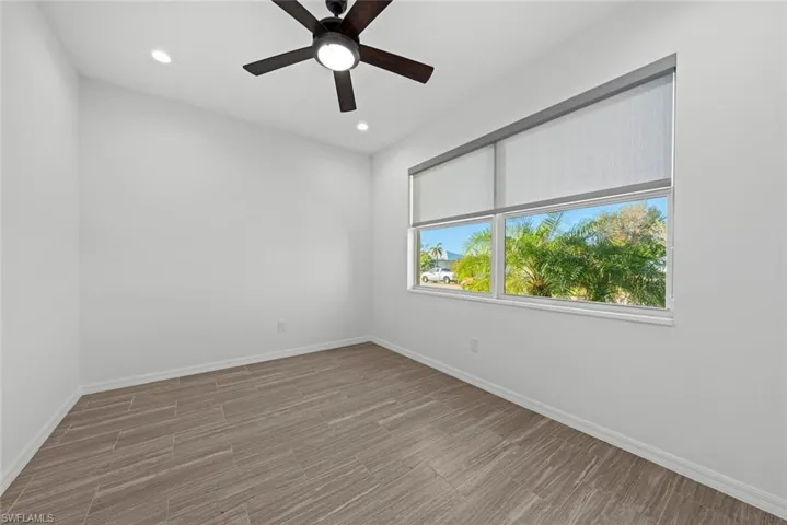 Empty room with hardwood / wood-style floors and ceiling fan