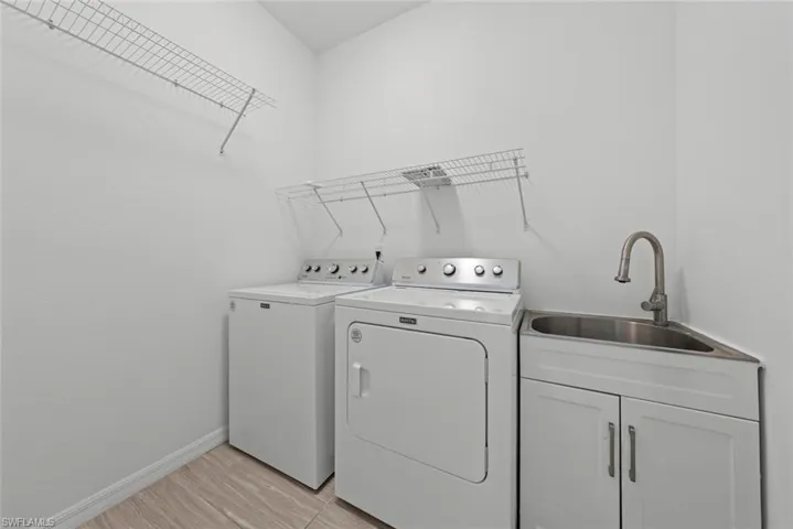 Laundry room featuring cabinets, sink, washer and dryer, and light hardwood / wood-style flooring