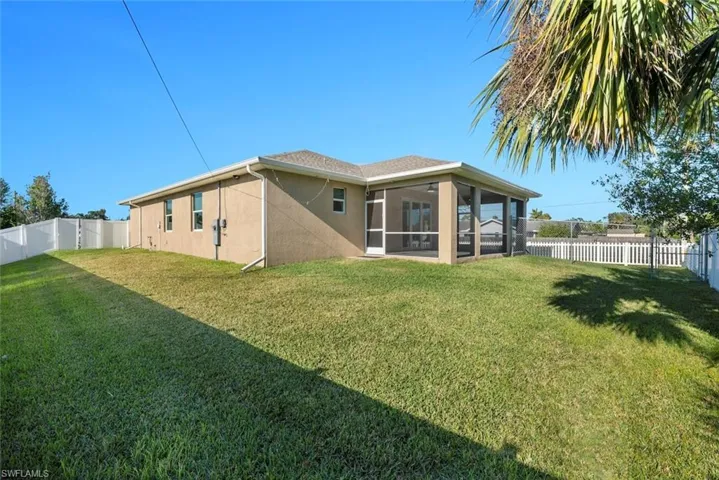 Back of property with a sunroom and a lawn