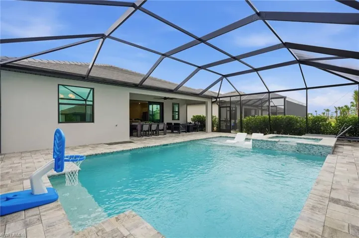 Screened lanai featuring a rectangular swimming pool with integrated spa and sun shelf
