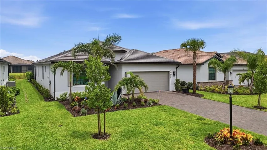 Contemporary single-story residence featuring a stucco exterior, tile roof, and a paver driveway