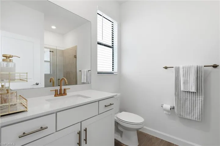 Bathroom featuring a white vanity with gold-finish hardware, a rectangular undermount sink, and a gold-finish faucet
