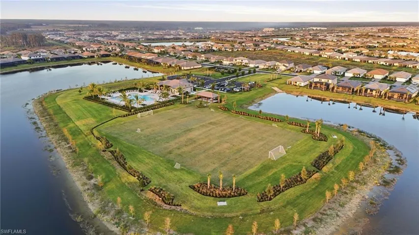 Expansive community green space with a large central field, surrounded by tranquil water features