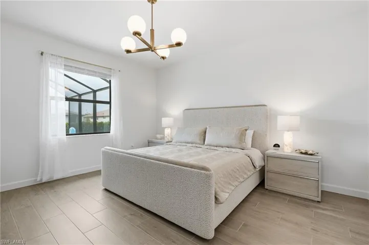 Bright interior featuring wood-finish flooring, a contemporary chandelier, white walls, and a large window with sheer drapery