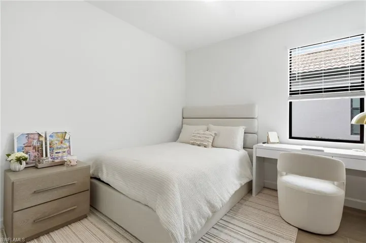 Bright room featuring a window with horizontal blinds, a neutral color palette, and light wood-finish flooring
