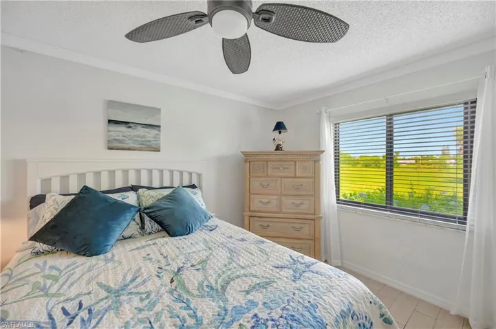 Bedroom with a textured ceiling, ornamental molding, and ceiling fan