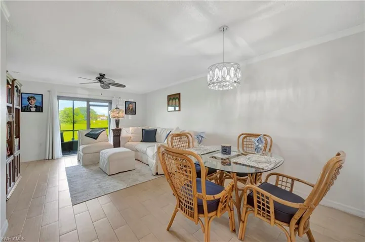 Dining space featuring crown molding, light hardwood / wood-style flooring, and ceiling fan with notable chandelier