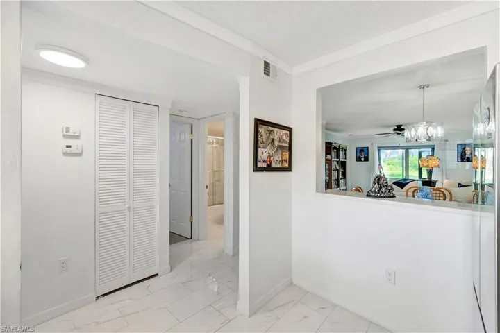 Corridor with crown molding and light tile patterned floors