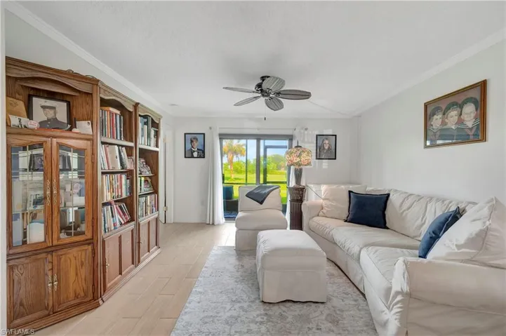 Living room featuring crown molding, light wood-type flooring, and ceiling fan