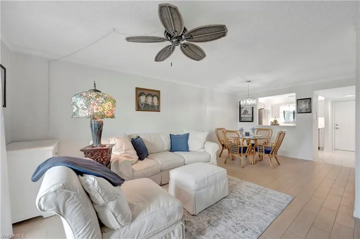 Living room featuring hardwood / wood-style flooring, ceiling fan with notable chandelier, and ornamental molding