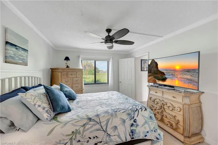 Bedroom featuring a textured ceiling, ornamental molding, and ceiling fan