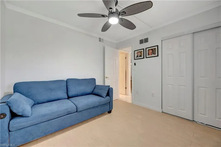 Living room featuring light wood-type flooring, ceiling fan, and ornamental molding