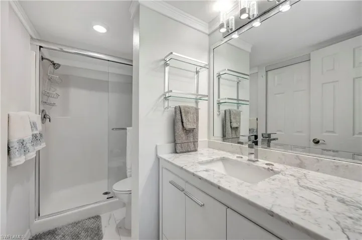 Bathroom with vanity, a shower with shower door, ornamental molding, toilet, and tile patterned flooring
